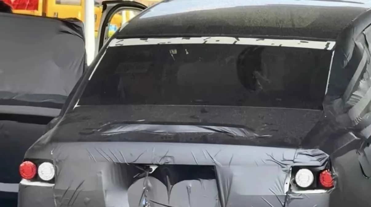 Rear view of a BYD Yangwang prototype vehicle covered in camouflage.